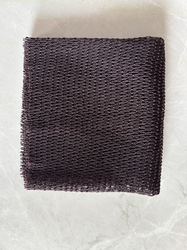 Black African net sponge laid flat on a pale floor